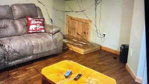 A living room with a leather sofa, a wooden coffee table with remotes, a television mounted on the wall, and a wooden cabinet. - Cabin 38 miles from Beach Mountain ski resort 5 miles from the lake in winery (Butler)