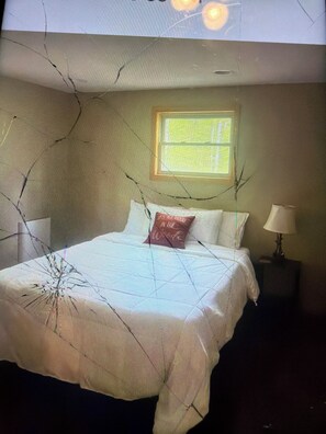 A bedroom with a bed, a window, and a nightstand with a lamp. - Cabin 38 miles from Beach Mountain ski resort 5 miles from the lake in winery (Butler)