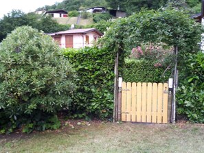 A wooden gate with a picket fence, surrounded by dense shrubbery and a hedge. - Casa Giuseppe by Interhome (Manerba)