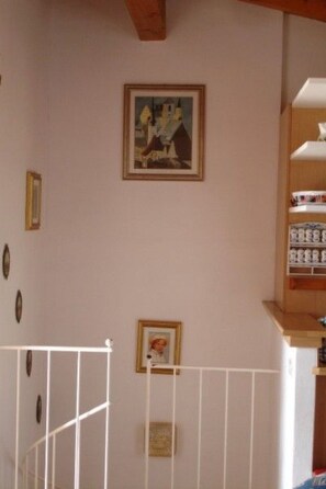 A room with a white railing, a framed picture on the wall, and a shelf with items. - Casa Giuseppe by Interhome (Manerba)