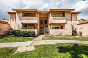 A two-story residential building with a central entrance, a staircase, and a small front yard with grass and a hedge. - Carlton Suite 1b/1b near UNLV (Las Vegas)