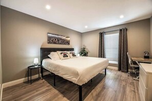 Une chambre à coucher comprenant un lit, une table de chevet, une lampe et un bureau avec une chaise.