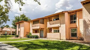 Un edificio residencial de varios pisos con techo plano, balcones y un césped bien cuidado.