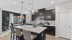 A modern kitchen with dark cabinetry, a central island, and pendant lighting. - Skye Canyon 3 bedrooms + Loft (Las Vegas)