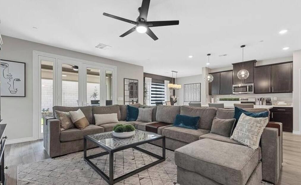 A modern living room with a sectional sofa, a coffee table, and a ceiling fan.