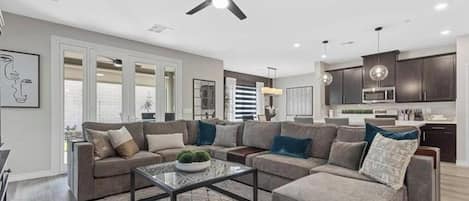 A modern living room with a sectional sofa, a coffee table, and a ceiling fan.