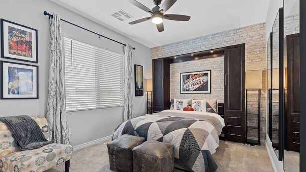 A bedroom with a bed, a chair, a ceiling fan, and a brick accent wall. - Skye Canyon 3 bedrooms + Loft (Las Vegas)
