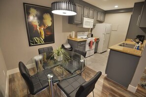 A modern kitchen with a glass dining table, black chairs, and a microwave. - Crawford suite 1b/1b near UNLV (Las Vegas)