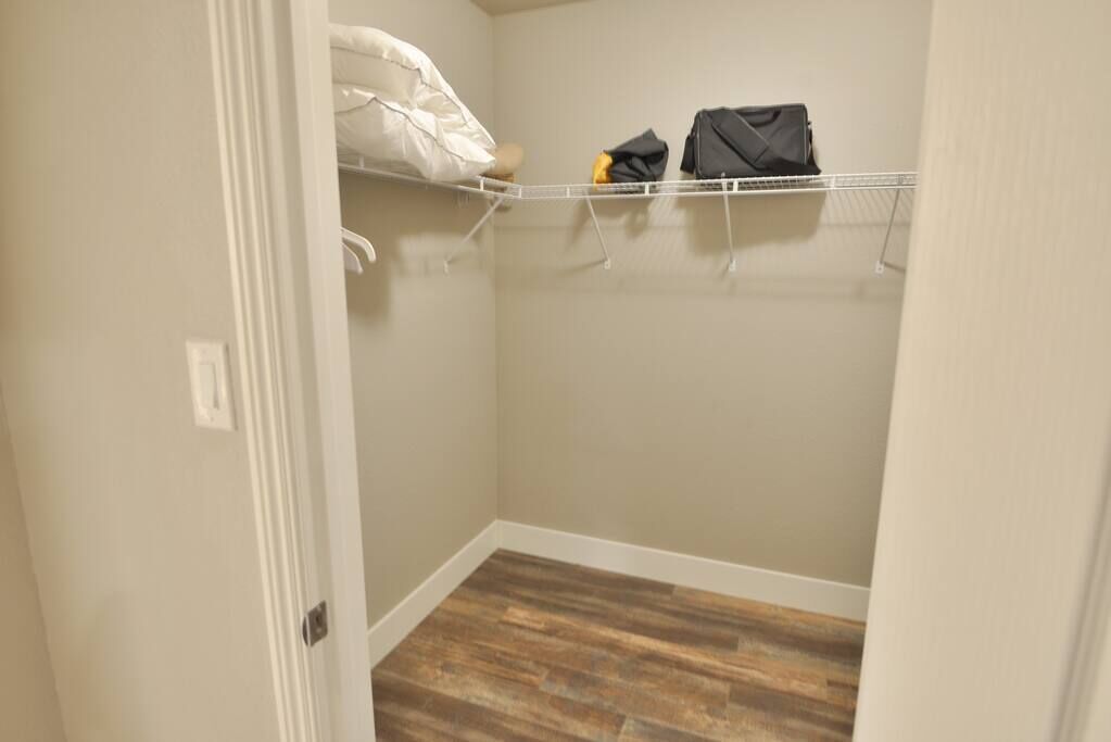 A closet with a wooden floor and a white door.