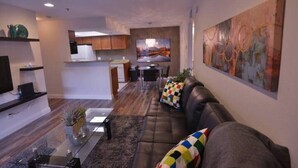Ein modernes Wohnzimmer mit einer Ledersofa, einem Glastisch und einem Gemälde an der Wand.