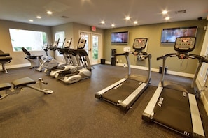 Une salle de sport équipée de tapis de course, de vélos d’appartement et d’appareils de musculation.