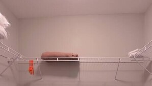 A closet with a metal shelf and a hanging rack, a dark wooden floor, and light-colored walls. - Nova Suite 1b/1b close to strip! (Las Vegas)