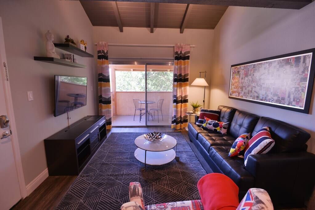 Ein modernes Wohnzimmer mit Fernseher, einer Couch, einem Couchtisch und einem gemusterten Teppich.
