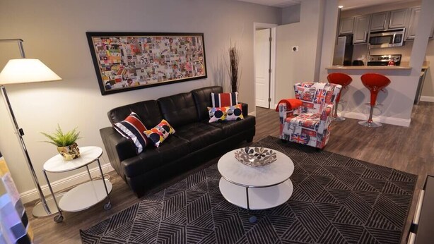 A modern living room with a black sofa, a round coffee table, and a patterned rug. - Nova Suite 1b/1b close to strip! (Las Vegas)