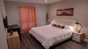A bedroom with a bed, a nightstand, a lamp, a TV, and a painting on the wall. - Nova Suite 1b/1b close to strip! (Las Vegas)