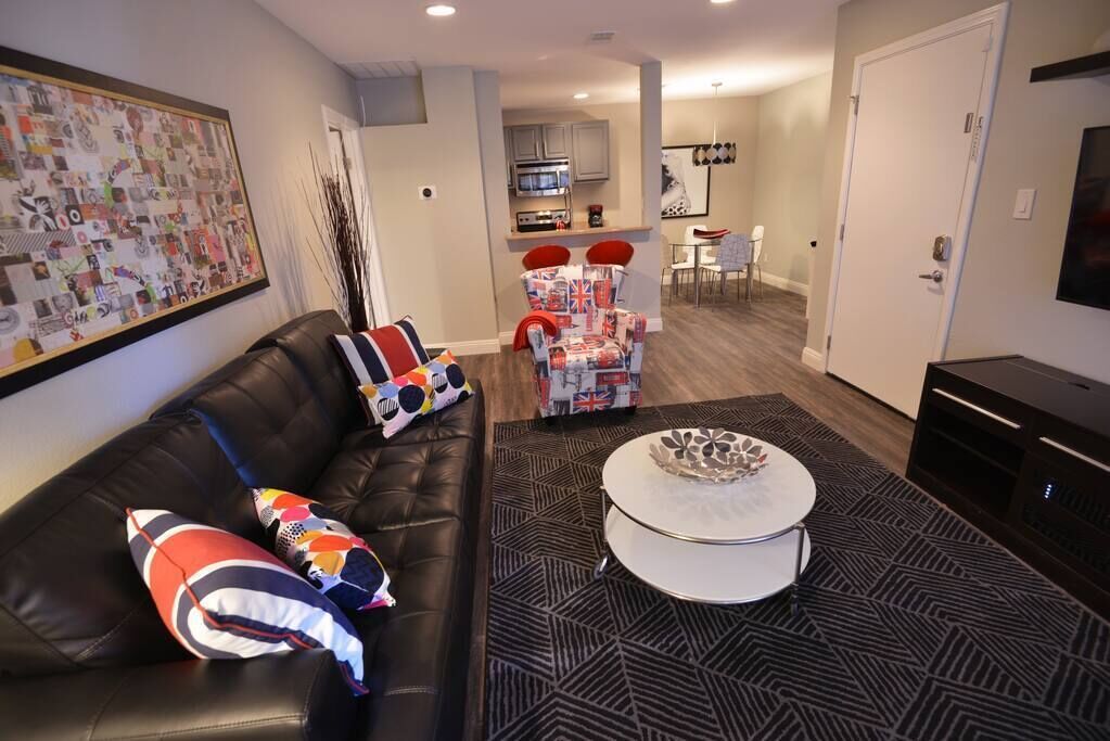 A modern living room with a black leather sofa, a patterned rug, and a round coffee table.