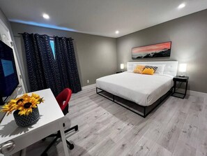 Een moderne slaapkamer met een bed, een bureau en een stoel.