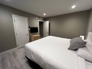 Ein Schlafzimmer mit Bett, Nachttisch, Fernseher und einer Tür.
