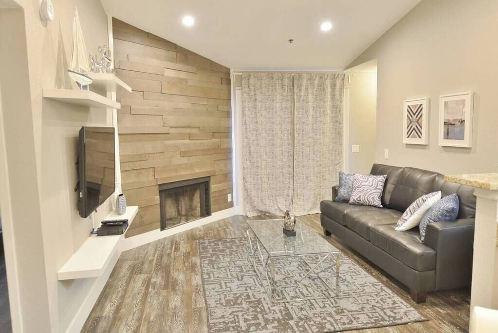 A living room with a fireplace, a sofa, a coffee table, and a patterned rug.