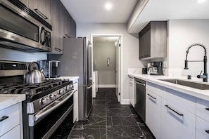 Eine moderne Küche mit Herd, Backofen, Kühlschrank und Kaffeemaschine.