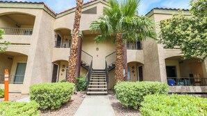 A multi-story building with a central staircase, surrounded by greenery and palm trees. - Ruxley Suite Luxury 2b/2b condo (Las Vegas)