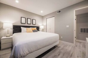A modern bedroom with a large bed, bedside lamps, and framed pictures on the wall. - Ruxley Suite Luxury 2b/2b condo (Las Vegas)