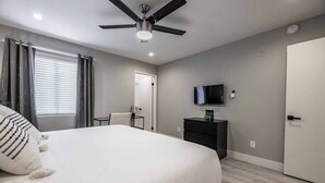 A bedroom with a bed, a ceiling fan, a television on a stand, and a door. - Ruxley Suite Luxury 2b/2b condo (Las Vegas)