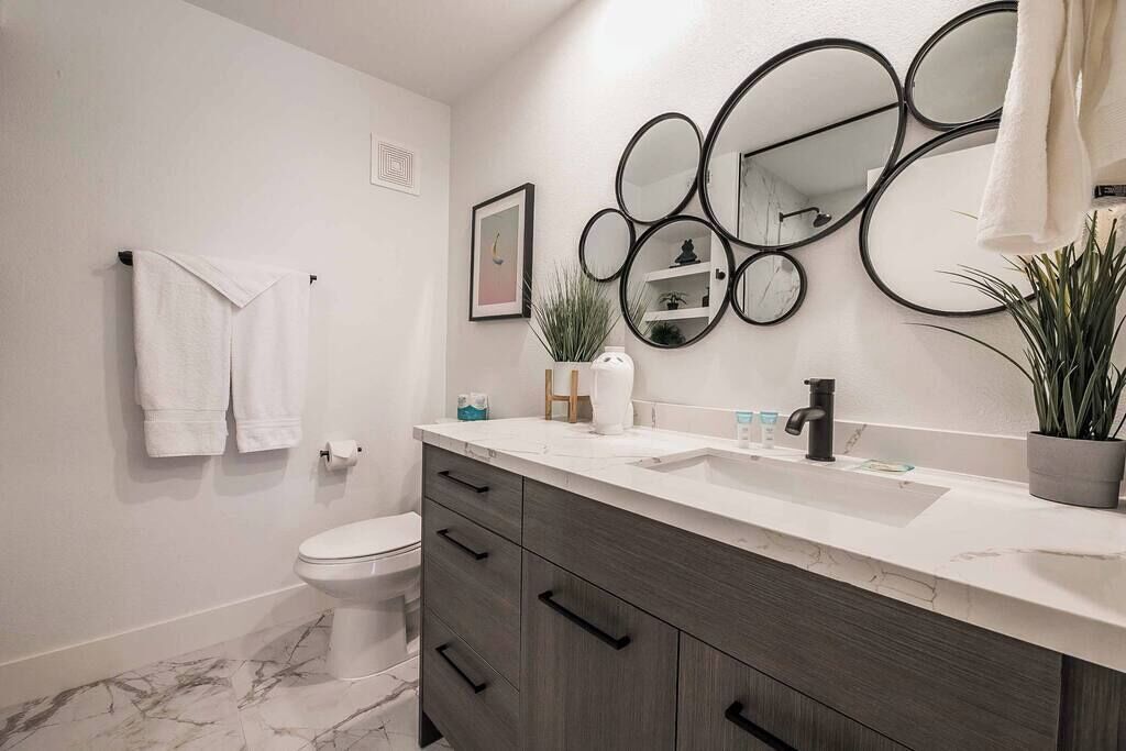 A bathroom with a toilet, a sink, a mirror, and a towel rack.