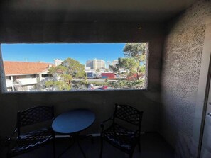 Ein Zimmer mit Blick auf eine Stadtlandschaft durch ein Fenster, zwei Sessel und ein kleiner Tisch.