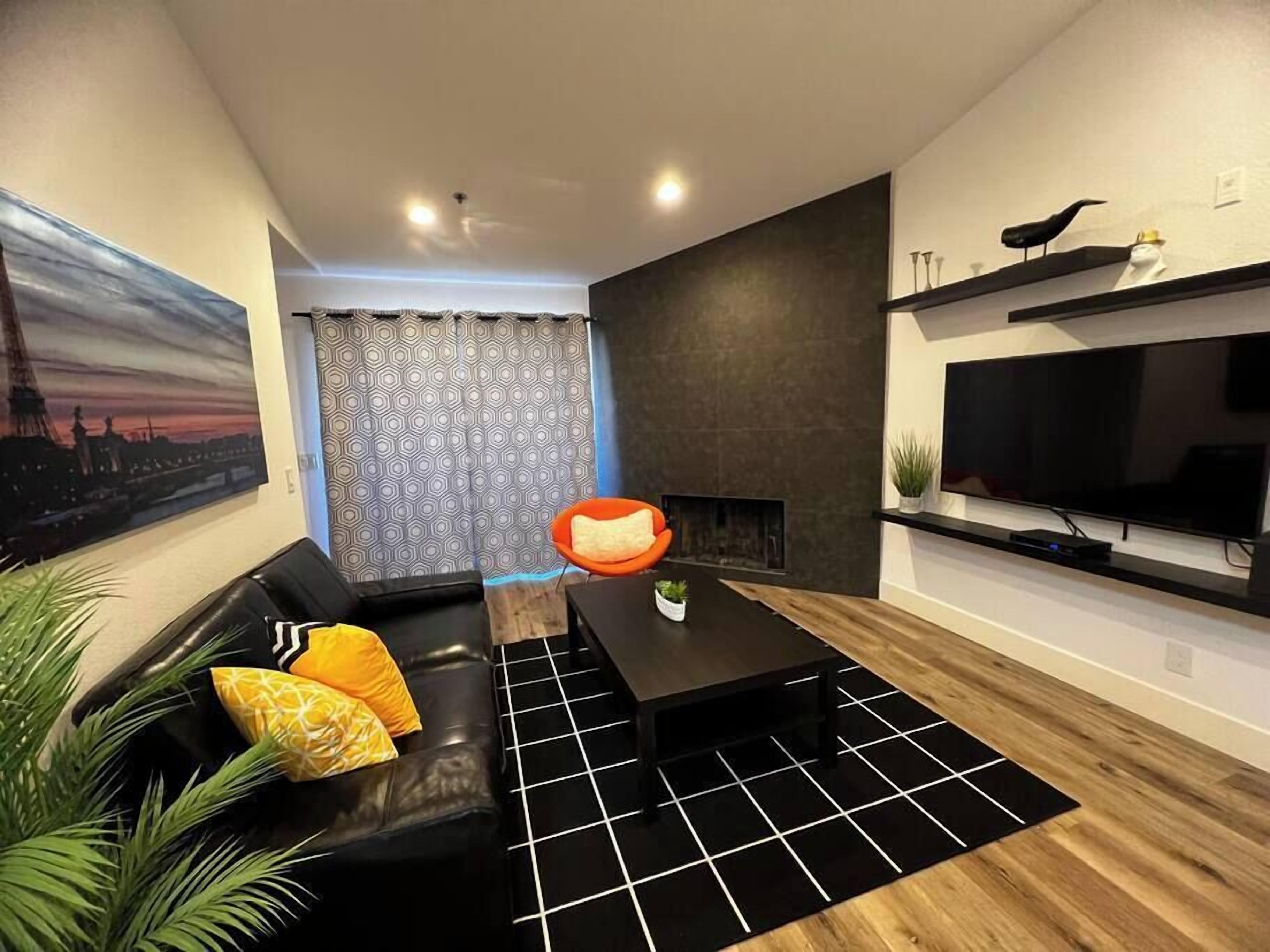 A modern living room with a black sofa, a coffee table, and a fireplace.