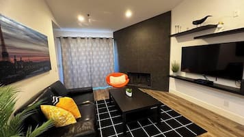 A modern living room with a black sofa, a coffee table, and a fireplace.