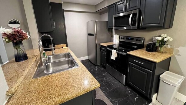 Una cocina moderna con encimeras de granito, electrodomésticos de acero inoxidable y armarios oscuros.