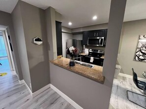 A modern kitchen with dark cabinets, stainless steel appliances, and a granite countertop. - Laguna Suite 2b/1b Near Strip (Las Vegas)