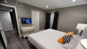 A hotel room with a bed, bedside table, lamp, and a television on the wall. - Dune Suite 2b/1b fully furnished (Las Vegas)