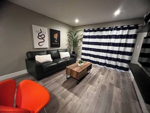 A living room with a black leather sofa, a wooden coffee table, and a striped curtain. - Dune Suite 2b/1b fully furnished (Las Vegas)
