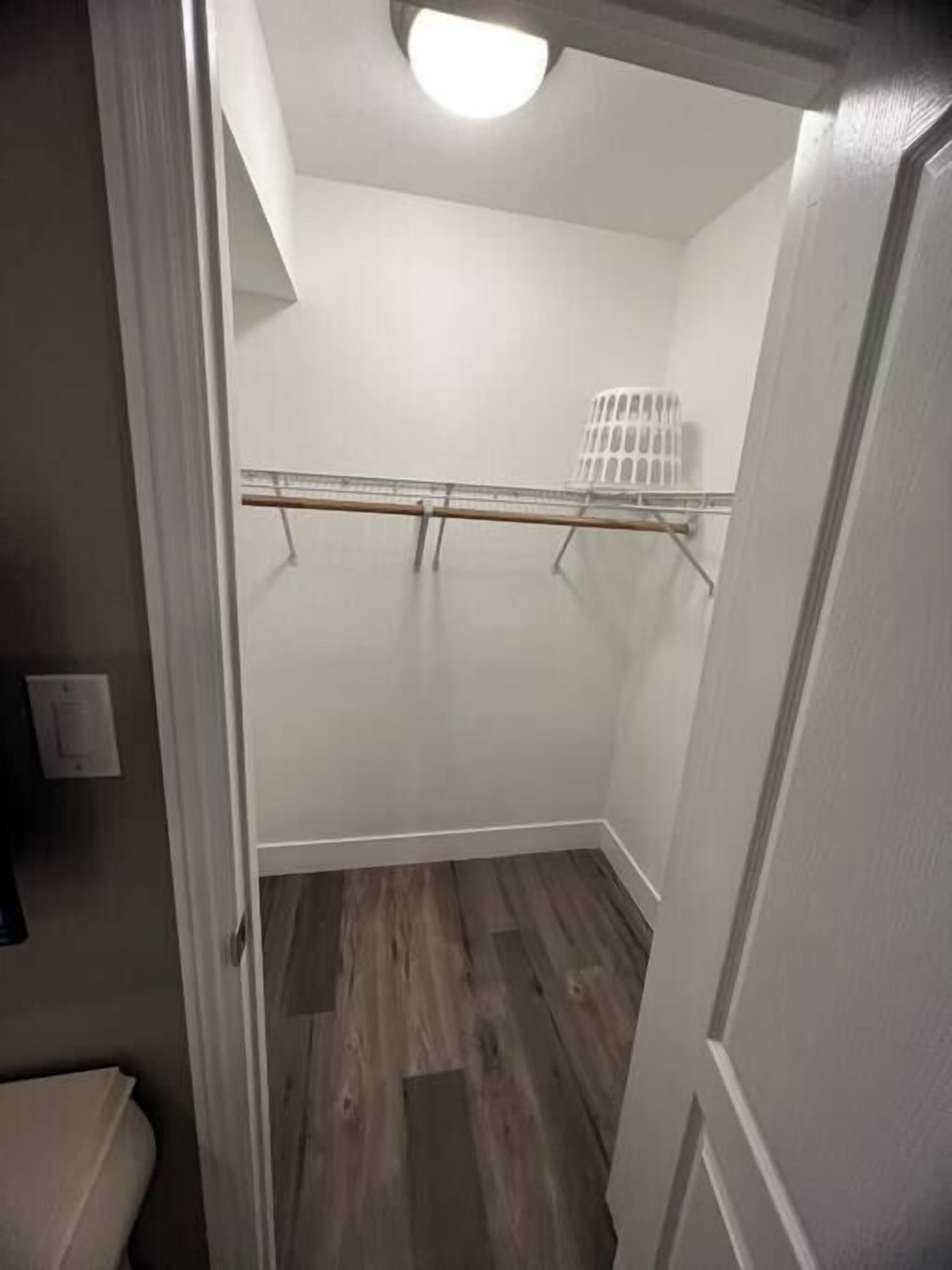 A narrow hallway with a wooden floor, a white door on the right, and a white radiator on the wall.
