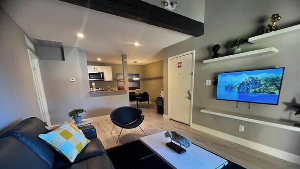 Ein modernes Wohnzimmer mit einer Couch, einem Couchtisch und einem an der Wand befestigten Flachbildfernseher.