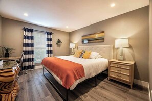 Ein Schlafzimmer mit Bett, Nachttischen, Schreibtisch und einem Fenster mit Vorhängen.