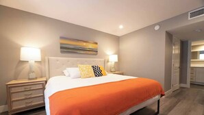 Een hotelkamer met een bed, twee nachtkastjes, een wanddecoratie en een zichtbare deur naar de badkamer.