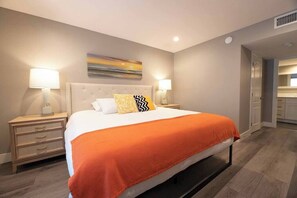 A hotel room with a bed, two bedside tables, a nightstand, a wall-mounted artwork, and a visible bathroom door. - Glasgow Suite 1b/1b entire condo (Las Vegas)
