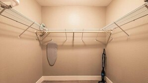 Een wasruimte met een metalen droogrek, een stofzuiger en een decoratief item aan de muur.