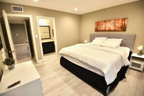 Un dormitorio con cama, mesitas de noche, un espejo y un cuadro en la pared.