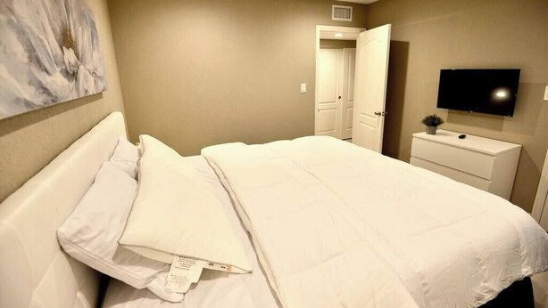 A hotel room with a bed, a television, a nightstand, and a door leading to another room. - Apex suite 2b/2b entire condo ! (Las Vegas)