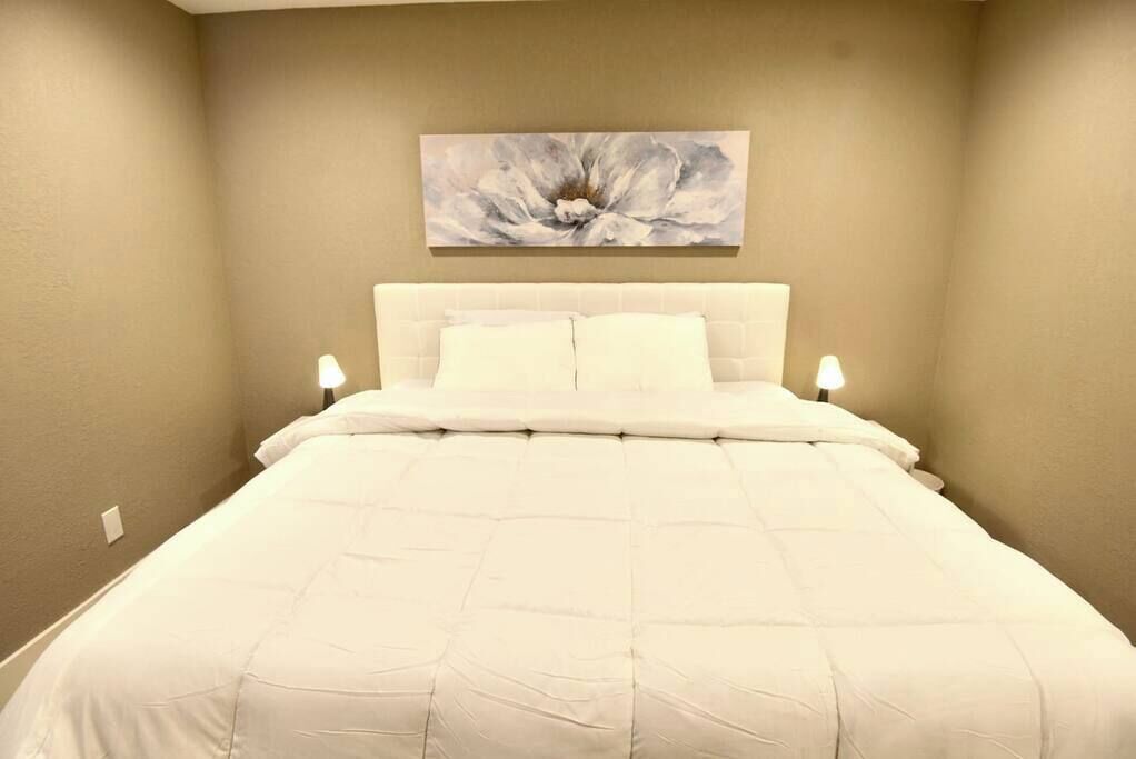 Un dormitorio con una cama grande, un cabecero y un cuadro colgado en la pared.
