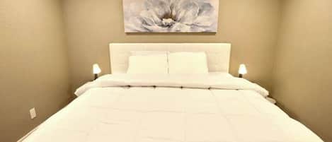 Un dormitorio con una cama grande, un cabecero y un cuadro colgado en la pared.