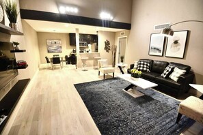 Ein modernes Wohnzimmer mit einer schwarzen Couch, einem Couchtisch und einem Essbereich mit Stühlen.
