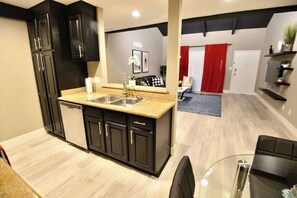 Una cocina moderna con muebles oscuros, un lavamanos doble y una mesa de comedor de vidrio.