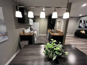 A modern kitchen with a dining table, pendant lights, and a potted plant. - Noma Suite Entire 2bed/2bath (Las Vegas)