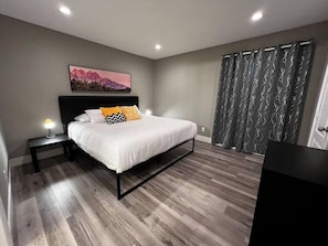A bedroom with a bed, bedside table, lamp, and a painting on the wall. - Noma Suite Entire 2bed/2bath (Las Vegas)