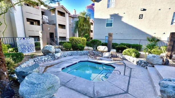 A pool area with a stone border, a lounge chair, and a sign indicating a spa rule. - Chelsea Suite 2b/2b Strip View! (Las Vegas)